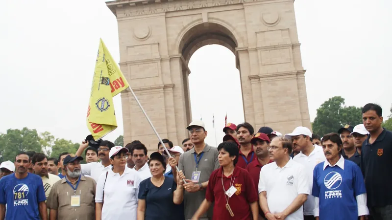 People gathered under India Gate in New Delhi at the start of a mass run, one of them holding a yellow flag.